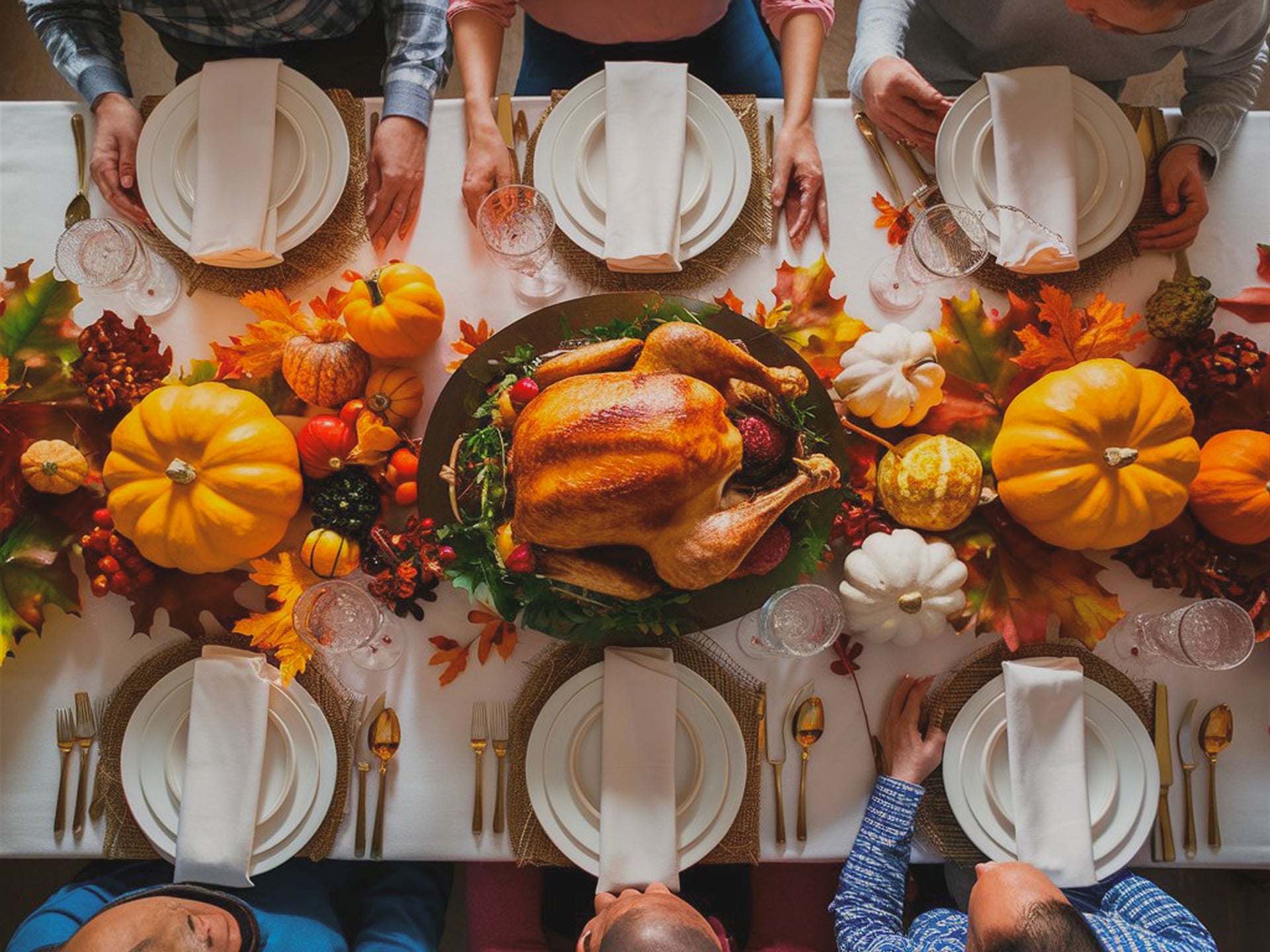 A Thanksgiving table set with a roasted turkey in the center, surrounded by pumpkins, autumn leaves, and place settings. Four people are seated around the table, ready to share the meal.