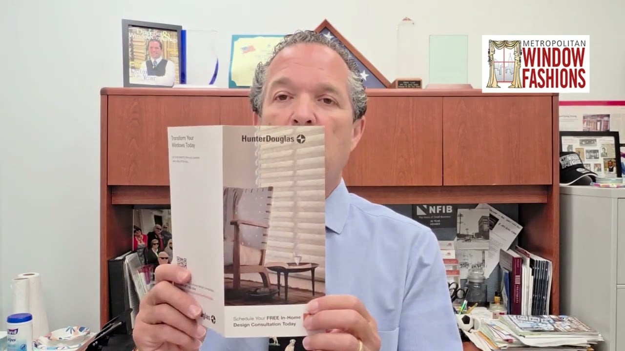 A man in a blue shirt holds up a Hunter Douglas window fashions brochure in an office. The Metropolitan Window Fashions logo is visible in the top right corner.
